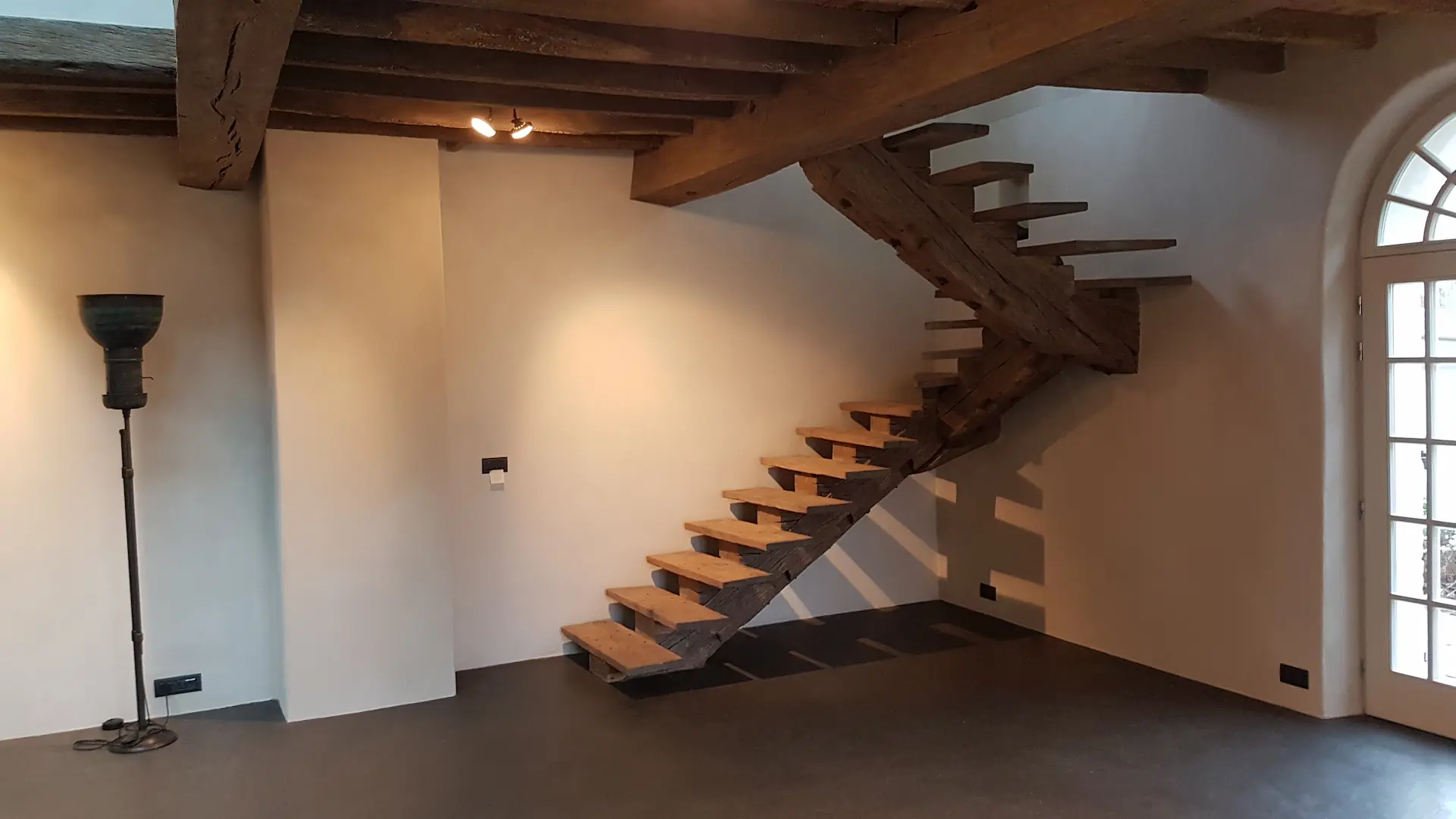 Pièce rénovée avec escalier en bois et spots encastrés au plafond