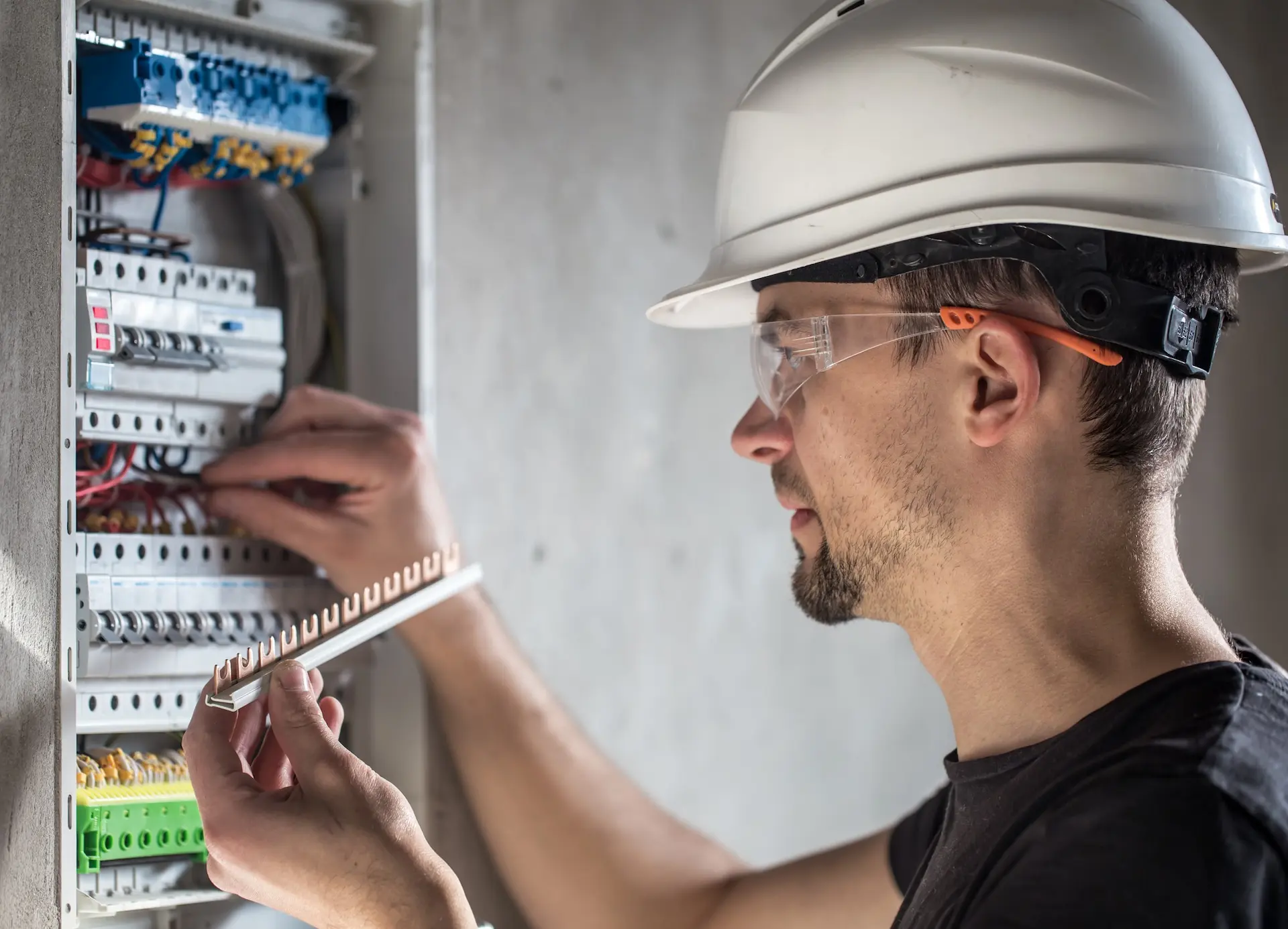 Électricien casqué câblant un tableau électrique